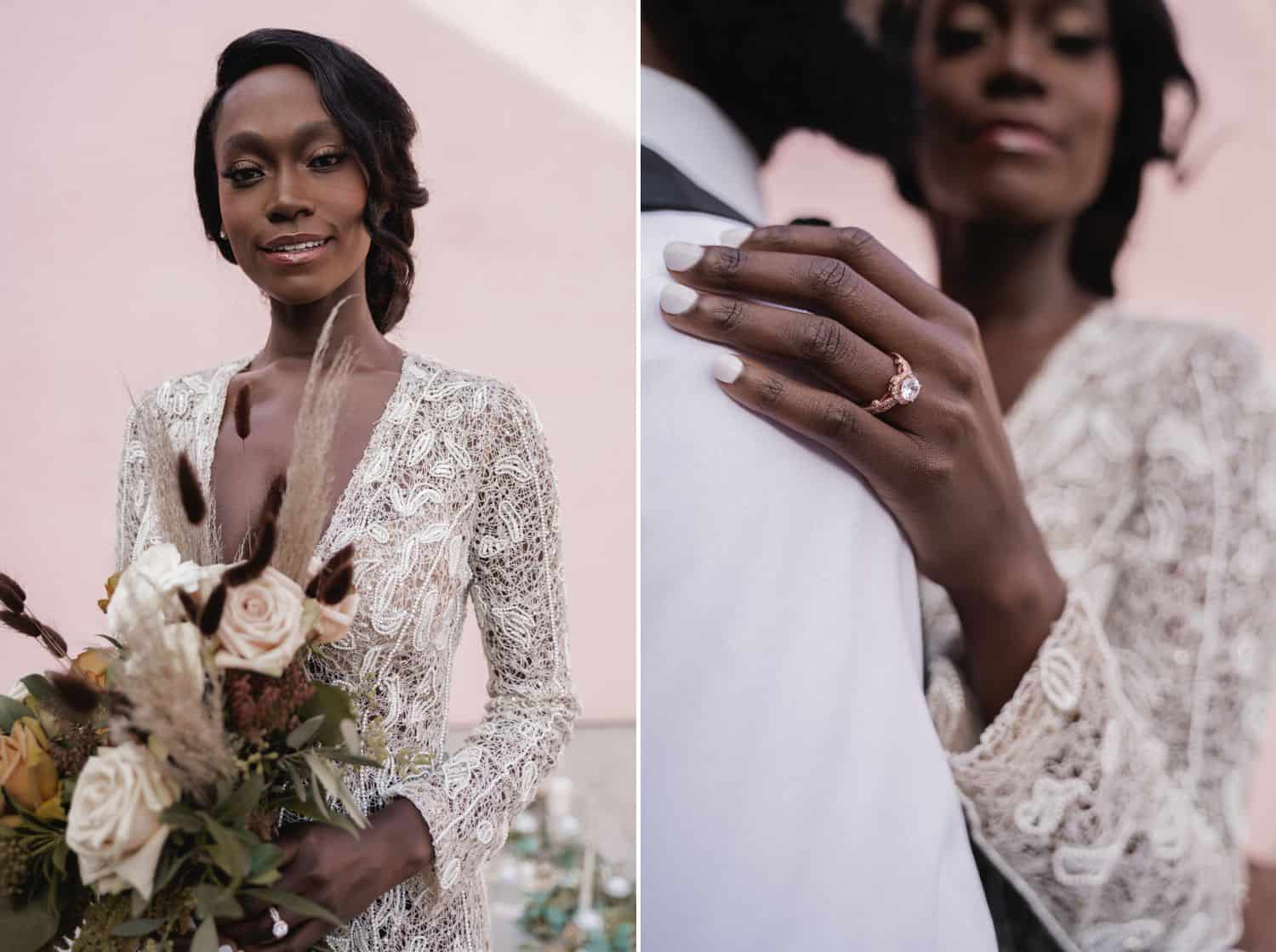 A Black bride in a lace jumpsuit stands in front of a pink wall with a stunning diamond engagement ring and a large bouquet of flowers.