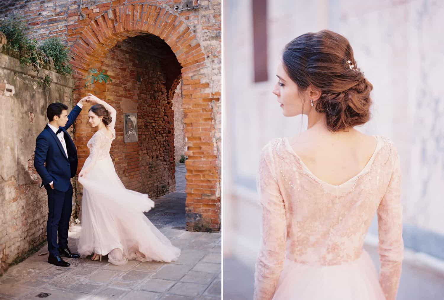 A groom in a blue tuxedo twirls a bride in a pink wedding dress in an Italian alleyway.